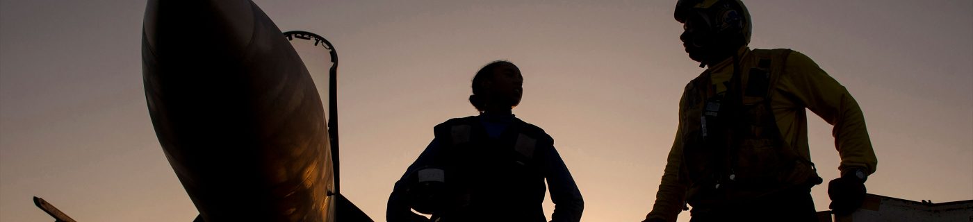 shadowed military personnel in front of plane