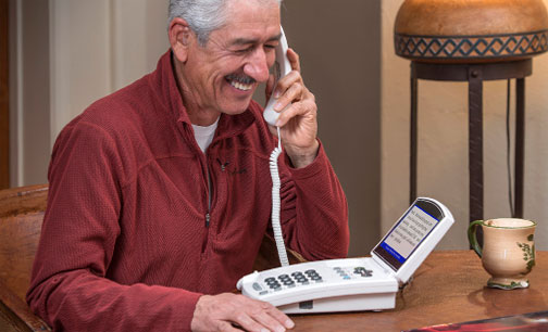 man talking on captioned telephone