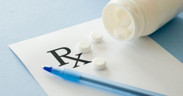 An open bottle of medicine tablets spilling onto a prescription tablet