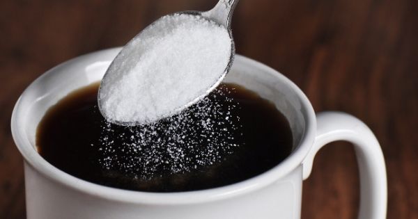 Dodanie łyżeczki cukru do filiżanki czarnej kawy